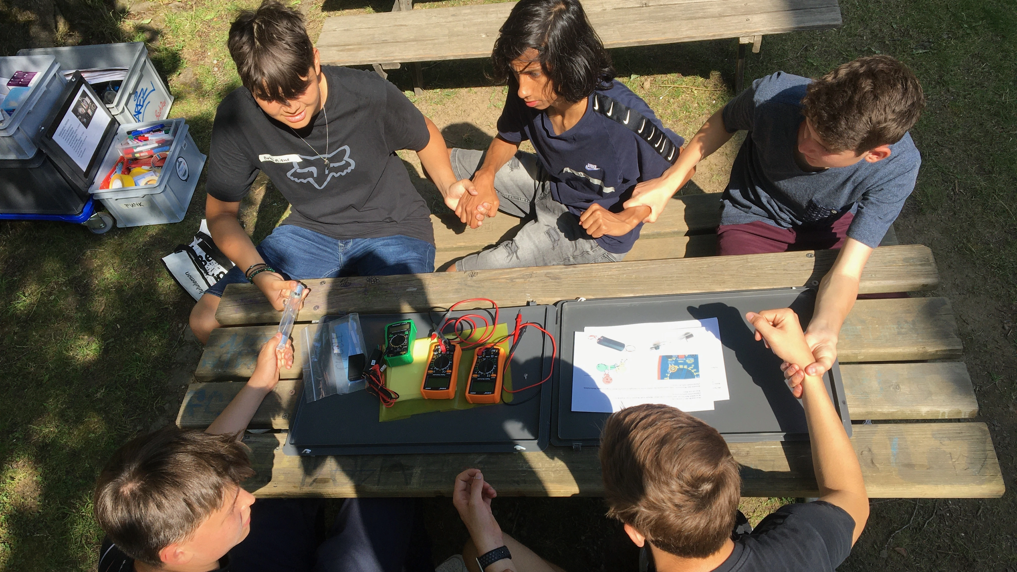 Jugendliche an einem Workshop zu nachhaltiger Energie machen ein Experiment an einem Tisch